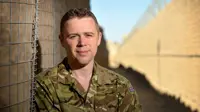 Portrait of a soldier smiling in uniform in a sandy landscape